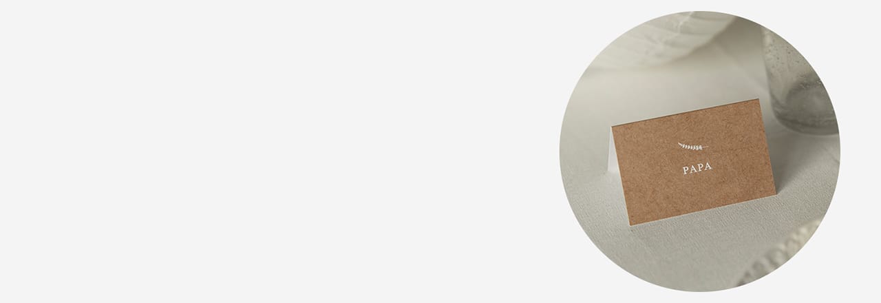 Nahaufnahme einer Tischkarte, schlichtes Design, mit Text "Papa", aufgestellt auf einem gedeckten Tisch